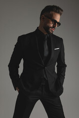 Fototapeta premium Handsome man wearing suit and sunglasses looking to side