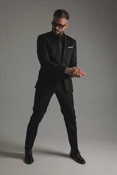 Serious man in suit rubbing hands and looking down