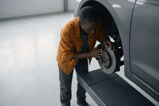Woman auto technician inspecting a brake disc in a car service bay