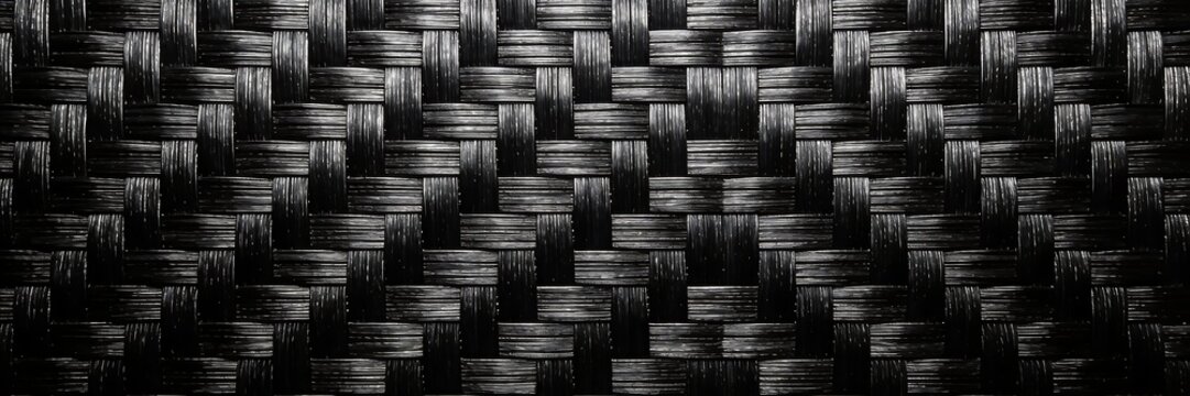 A tightly interlaced carbon fiber weave texture displays uniform monochrome black and dark gray tones in a seamless flat pattern