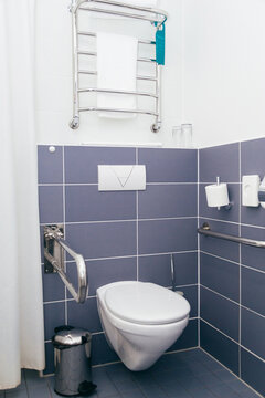 Wall-Mounted Toilet With Grab Bars And Heated Towel Rack In Accessible Bathroom