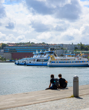 Gothenburg, Sweden - July 26 2026: People relaxing beside docked ferries on Gothenburg waterfront.
