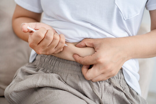 Close-up of a person giving themselves an insulin injection in the belly fat for diabetes treatment, hormone therapy, or weight loss pen medication management at home.