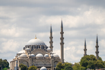 Historic Ottoman mosque architecture featuring grand domes and towering minarets against cloudy sky. Cultural heritage landmark representing traditional Islamic design and historical tourism © Tetiana