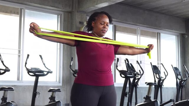 African American woman training with resistance bands in a gym, improving strength, mobility and fitness while promoting healthy aging.