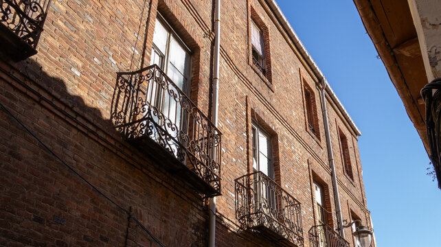 Fachada de edificio de ladrillo con balcones de forja bajo cielo azul