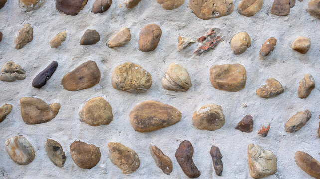 Muro de cemento con piedras incrustadas dispuestas en filas