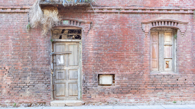Fachada de ladrillo rojo con puerta de madera antigua ventana y balc&oacute;n