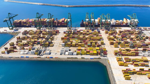 Sines, Setubal, Portugal - 20 June 2026: Aerial view of the Port of Sines, with large cargo ships, rows of colorful shipping containers, and industrial gantry cranes along the coast.