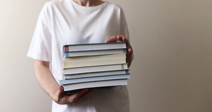 Person holding a stack of books, person holding a stack of books, book theme, reading theme, lifestyle theme
