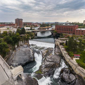 Spokane, United States - 15 August 2026: Aerial view of Spokane Falls with the surrounding urban landscape, historic brick buildings, and the river flowing through the city under a cloudy sky.
