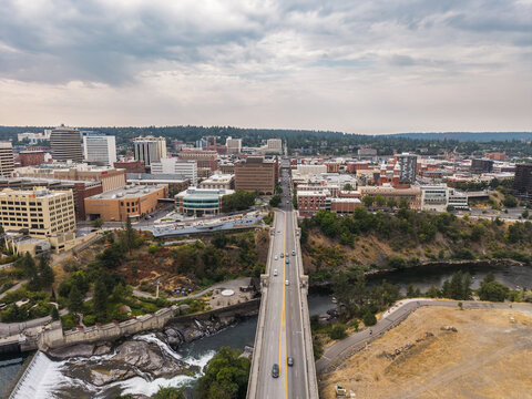 Spokane, United States - 15 August 2026: Aerial view of the Monroe Street Bridge spanning the Spokane River with the downtown skyline and urban landscape under a cloudy sky.