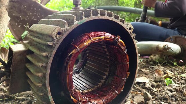 Close Up View of Copper Winding Insulated Coils exposed inside an open electric induction motor casing during field repair operations, capturing technical engineering concepts of machinery maintenance