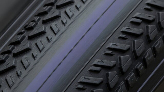 A highly detailed macro shot of a road bike tire with a textured tread pattern and smooth center, captured in a widescreen cinematic composition to highlight high performance gear.