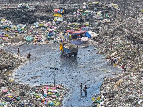 Dhaka, Bangladesh - 27 August 2026: Aerial view of Aminbazar Landfill with waste pickers sorting through piles of trash and a truck unloading refuse.
