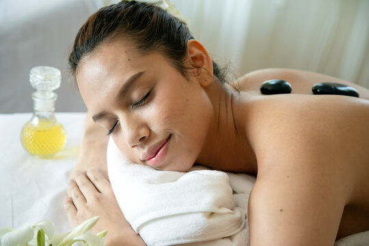 Woman relaxing during hot stone spa therapy with massage oil, closed eyes and gentle smile, wellness, self care, relaxation, beauty treatment and peaceful body care