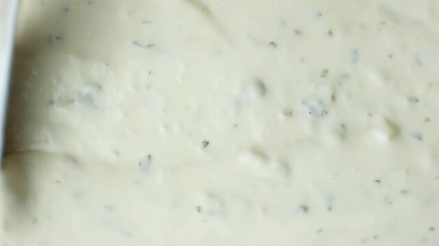 Top view of a knife smoothing creamy tartar sauce texture