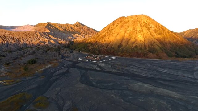 Aerial view of Pura Luhur Poten temple situated on the volcanic sand plains of Mount Bromo with dramatic mountain slopes in Kecamatan Sukapura, Jawa Timur, Indonesia.