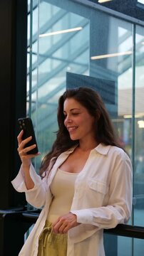 Beautiful woman holding her mobile phone and smiling during a video conversation indoors