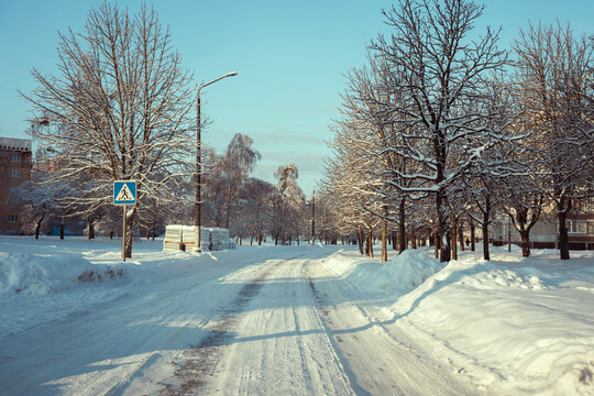 Winter road with tire tracks and frost covered trees