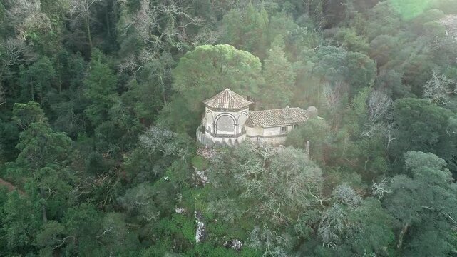 Aerial view of the historic stone chapel nestled within the dense, lush greenery of the Bucaco National Forest in Luso, Aveiro District, Portugal.