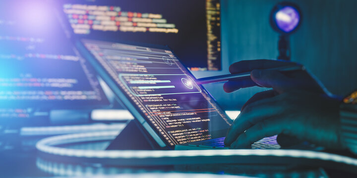 Futuristic software development concept: Programmer using a stylus on a touchscreen laptop with glowing digital interface and code.