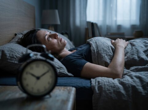 Woman awake in bed at night, staring at clock, struggling with insomnia and anxiety