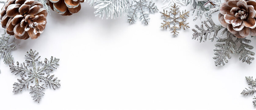 Christmas border with pine cones and silver snowflakes on white background