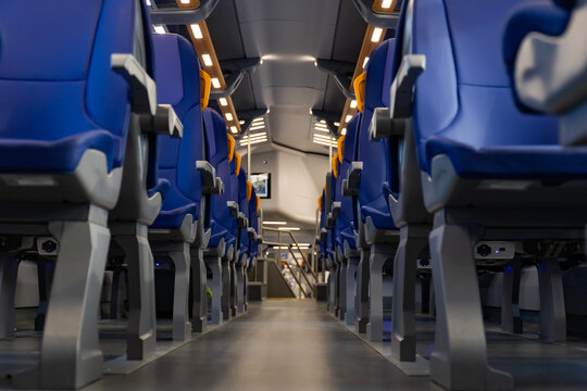 Empty blue passenger seats with yellow handles inside modern train carriage, showing travel