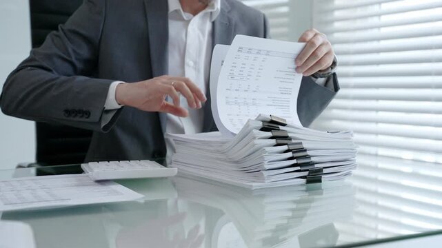 Businessman's hands are busy managing and organizing a large stack of financial papers and business documents