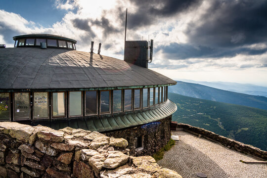 Karpacz, Poland - 28 July 2026: View of the Snezka mountain observatory with its distinctive circular architecture, stone walls, and panoramic mountain views under a dramatic cloudy sky.