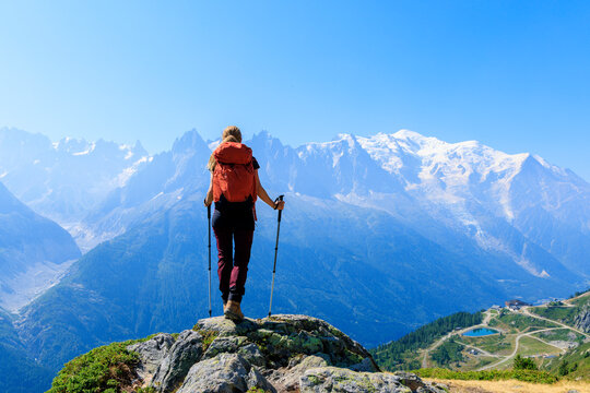 Female hiker with backpack standing on mountain peak looking at Mont Blanc view in Chamonix France