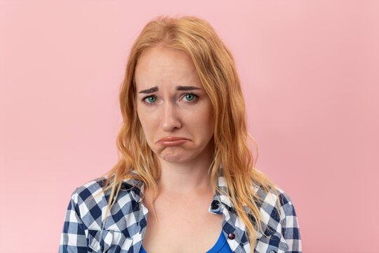 Young woman with blonde hair and green eyes showing a sad expression, with furrowed brows and downturned lips, reflecting concepts of disappointment, regret, and emotional distress