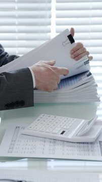 Professional hands reviewing important accounting documents. Managing financial paperwork. Calculating expenses. And organizing business reports on an office desk