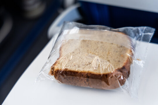 Bloated package of a piece of cake packed in transparent plastic bag in airplane cabin due to pressure in airplane flying high altitude.