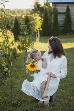 a cute five-year-old girl with mother in a white dress are playing in a green summer garden. happy childhood