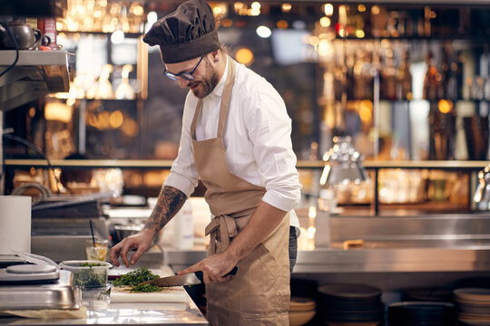 Chef cutting prasley. Cook in Professional Modern  kitchen, restaurant concept