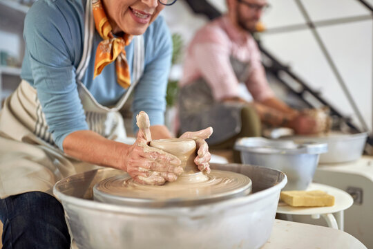 close up of woman wet hands making clay pot on wheel at pottery studio. Creative, hobby ,activities concept