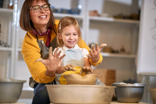 smiling studnet with dirty hands while making pot from clay on pottery workshop.  Creative, hobby ,workshop  concept