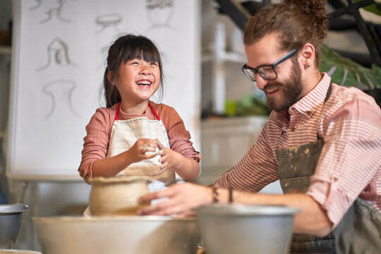 Happy Chinese girl making clay pot on pottery workshop.