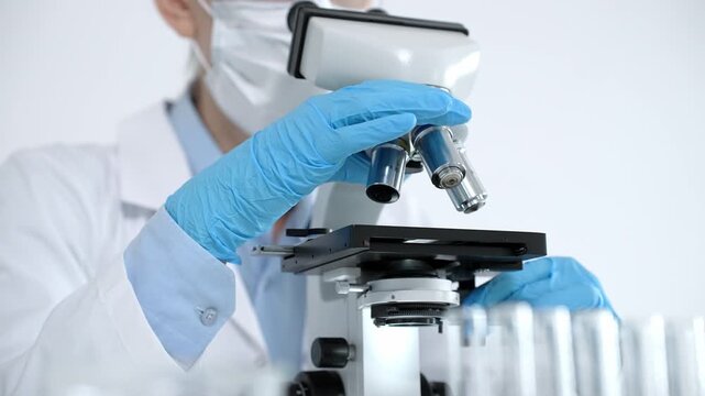 Scientist in a lab coat and protective gear precisely adjusting a microscope, conducting essential scientific research for medical advancements, and developing new healthcare solutions