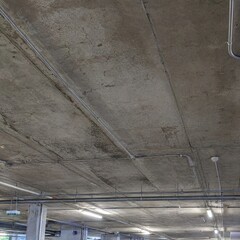 Obraz premium Concrete ceiling with exposed pipes and lighting in a parking garage 