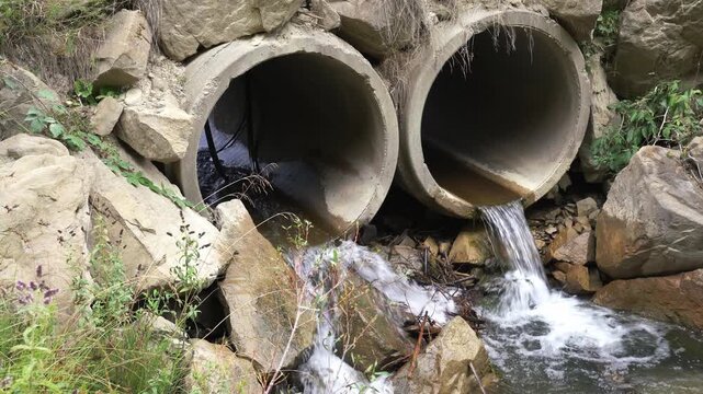 Small clean river flowing through concrete pipes in Transylvania, Romania.