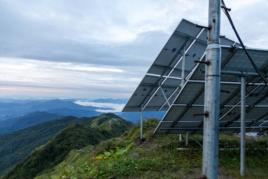 Pokhara, Gandaki Province, Nepal - 27 August 2026: View of solar panels on a mountain ridge along the Mardi Himal Trek with green slopes and distant peaks under a cloudy sky.
