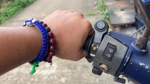 Motorcycle Grip: A close-up shot of a hand holding the throttle of a motorcycle, adorned with colorful bracelets, ready to embark on a journey.