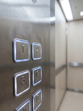Modern elevator control panel with illuminated stainless steel floor buttons.