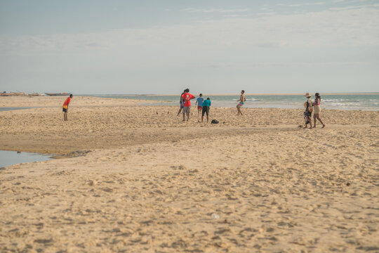Morondava, Menabe, Madagascar - 29 June 2026: View of a group of people playing soccer and walking on the sandy beach under a clear sky.