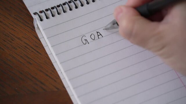New Year Goals 2027. Woman's Hand Writing in Notebook Goals List. Concept of New Year Planning.