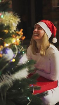 Opening christmas gifts. Woman receives the christmas gift near christmas tree. Christmas at home. Happy woman near christmas tree. Weihnachten zu hause. Red advent calendar near christmas tree.