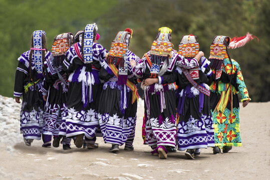 Chitral, Khyber Pakhtunkhwa, Pakistan - 16 May 2017: View of women in traditional Kalash attire with colorful headpieces and black dresses walking together at the Chilam Joshi festival.